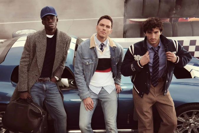 Three male models posing beside a blue vintage sports car for the Tommy Hilfiger Fall 2025 ad campaign.