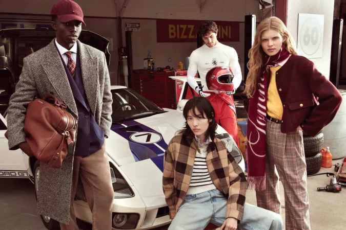 Five models posing inside a garage setting next to a white race car for Tommy Hilfiger Fall 2025 campaign.