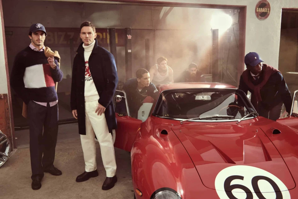 Group of six models posing around a vintage red sports car inside a garage for Tommy Hilfiger Fall 2025 campaign