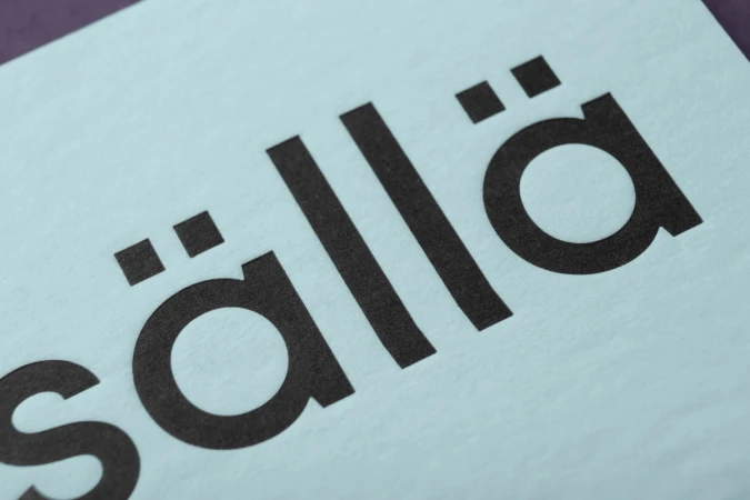 Close-up macro shot of black embossed typography reading Sisällä on textured light blue paper stock.