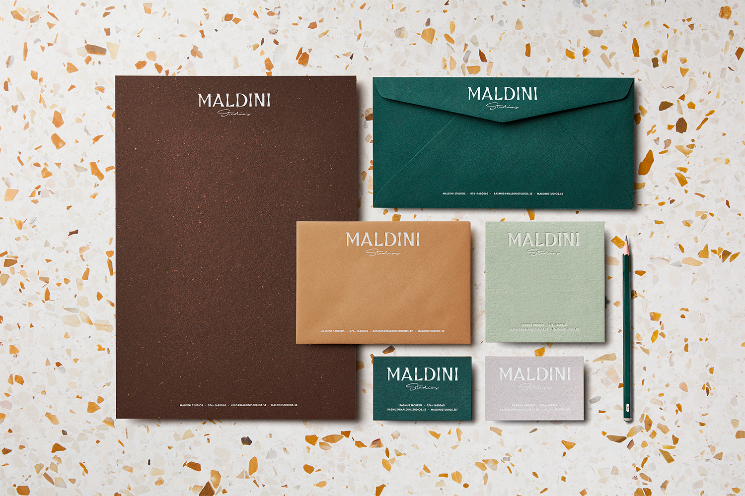 Flat lay of Maldini Studios corporate stationery including letterhead, envelopes, and business cards on terrazzo