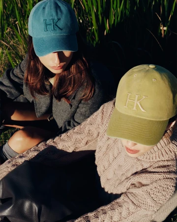 Two women outdoors wearing embroidered caps and knitwear for Helen Kaminski fall campaign