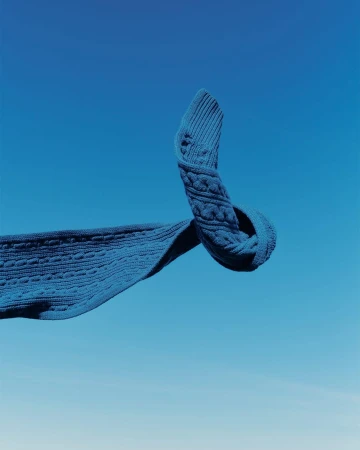 A knitted blue scarf curved against a vivid clear blue sky