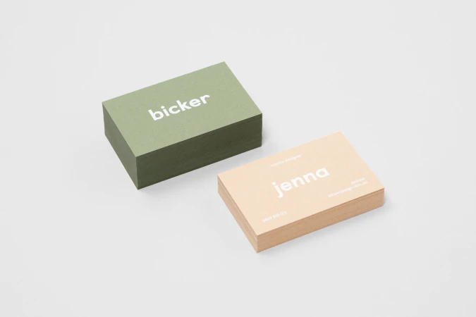 Two stacks of business cards in sage green and peach arranged diagonally on a plain white studio background.