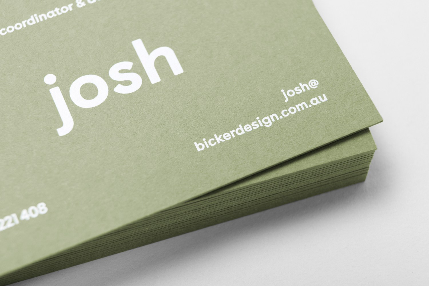 Close-up of a stacked stack of olive green business cards with white sans-serif typography showing the name josh