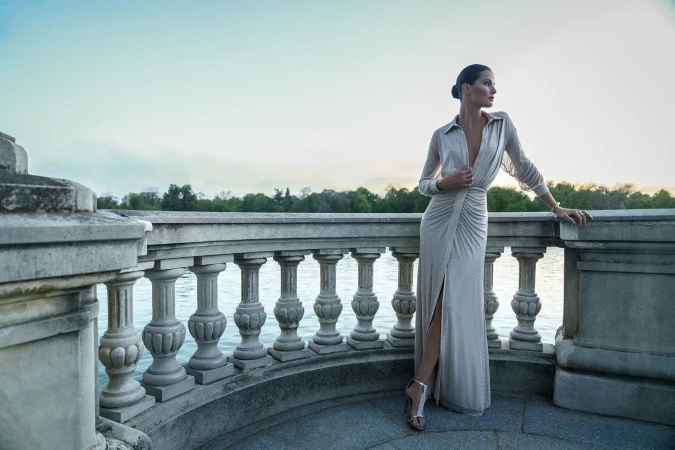 Model Isabeli Fontana posing on a stone balcony by the water for BCBGMAXAZRIA Fall 2025 campaign