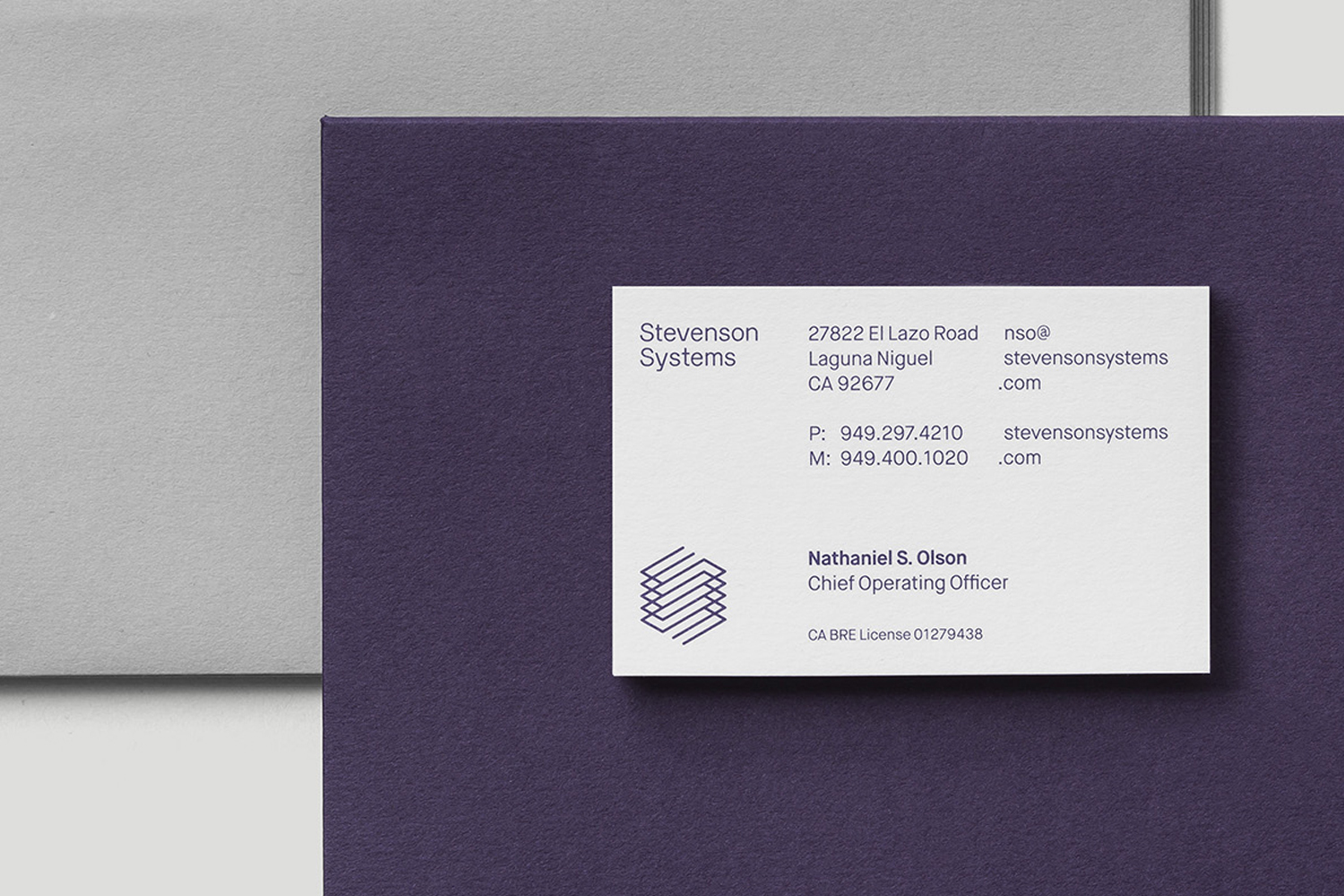 Stevenson Systems business card featuring clean typography and a geometric logo atop deep purple and grey textured paper stock.
