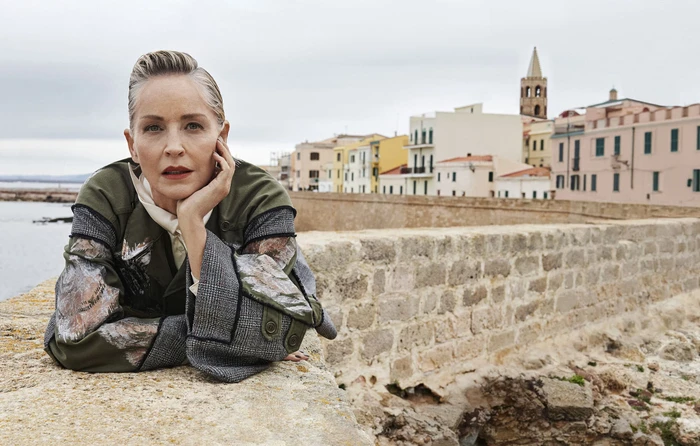 Sharon Stone leaning on a stone wall overlooking a coastal town in an ad campaign for Antonio Marras