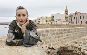 Sharon Stone leaning on a stone wall overlooking a coastal town in an ad campaign for Antonio Marras