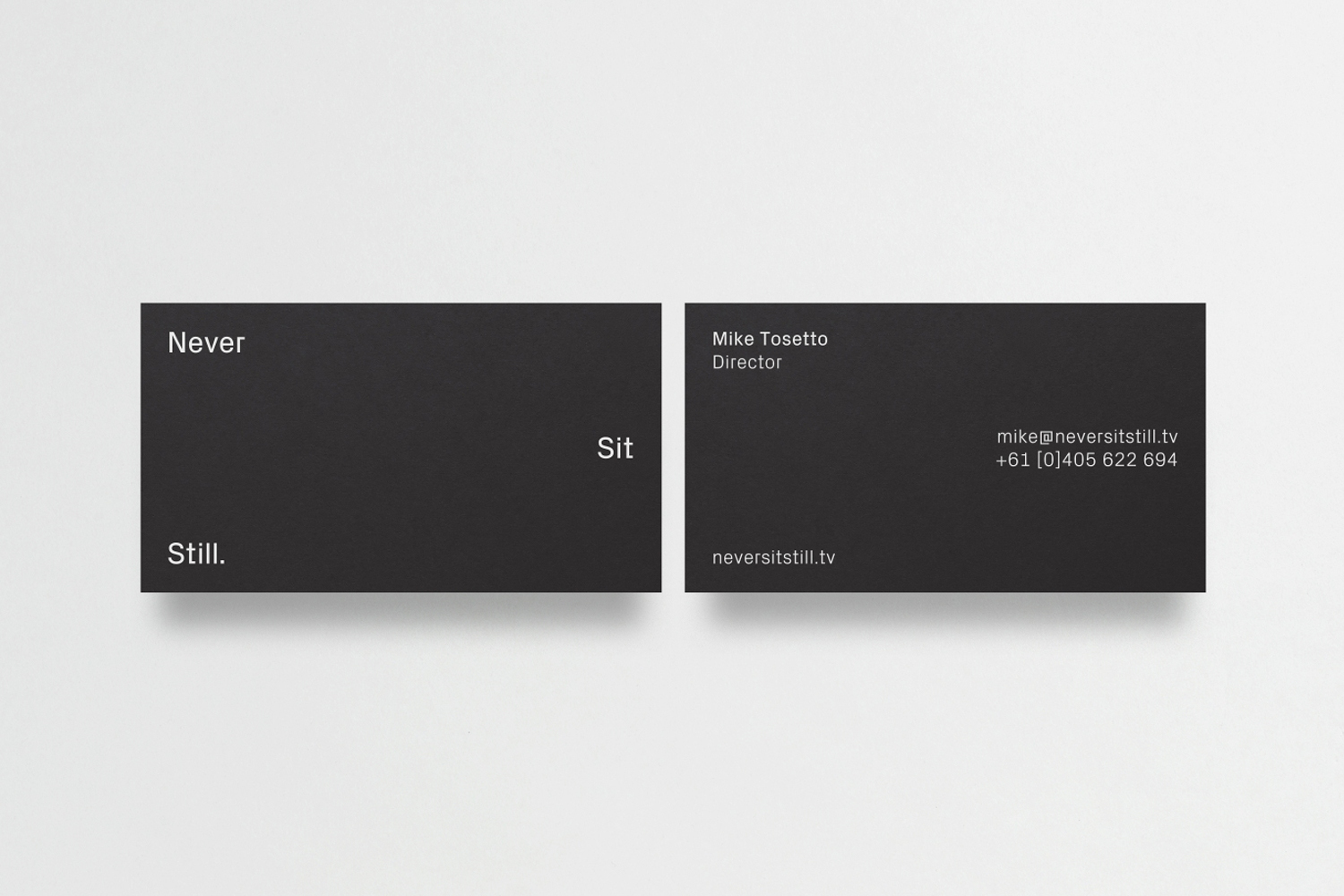 Two black business cards featuring minimalist white typography set against a clean white background surface.