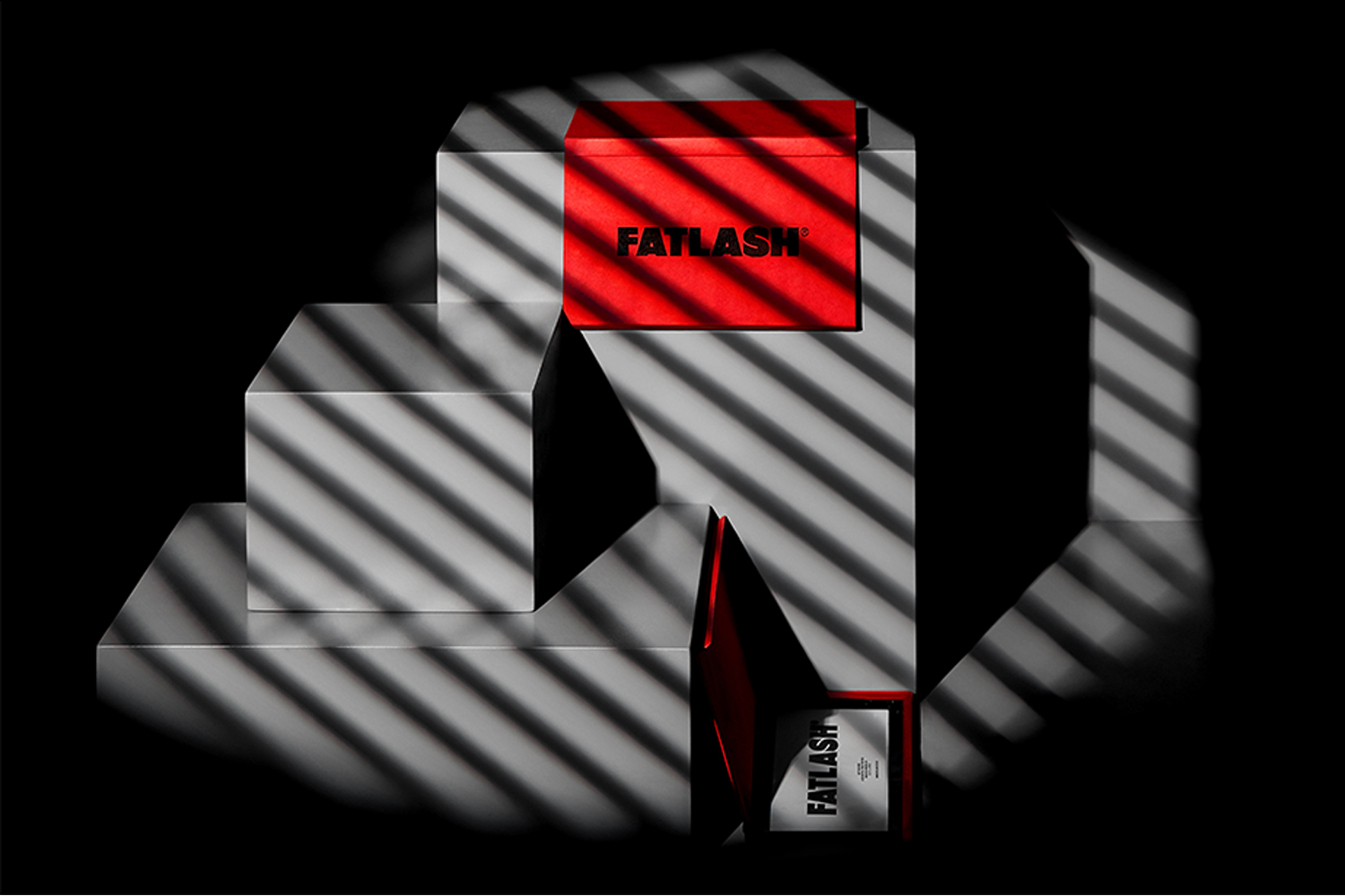 Product packaging for Fatlash featuring red and silver geometric boxes under patterned shadows