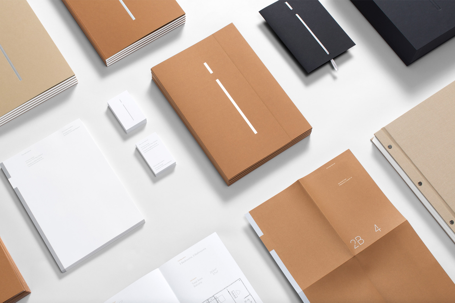 Flat lay of corporate stationery including notebooks, folders, and business cards in neutral earth tones on a white background