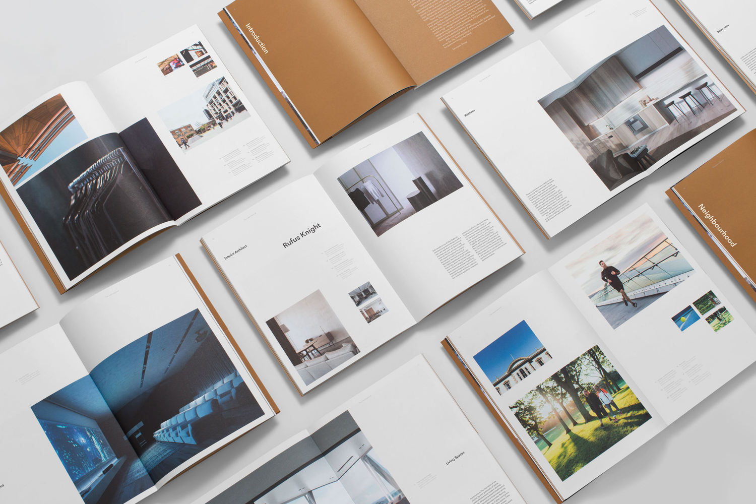 Flat lay of multiple open printed books and brochures showcasing brand identity and editorial layouts on a white background