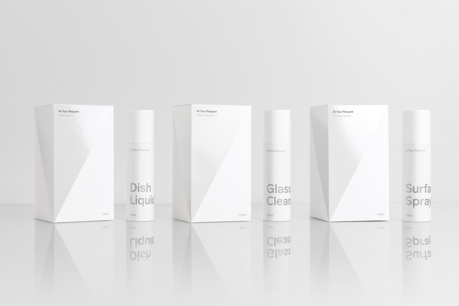 Minimalist product photography featuring white packaging boxes and spray bottles on a reflective white surface.