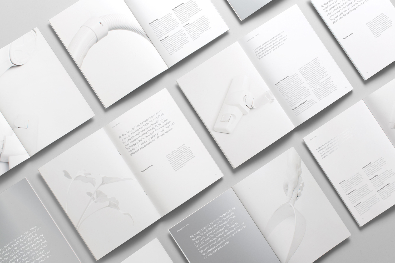 Flat lay of open brochures and manuals featuring minimalist typography and clean product photography on white background.
