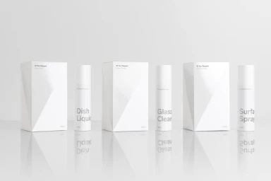 Minimalist product photography featuring white packaging boxes and spray bottles on a reflective white surface.