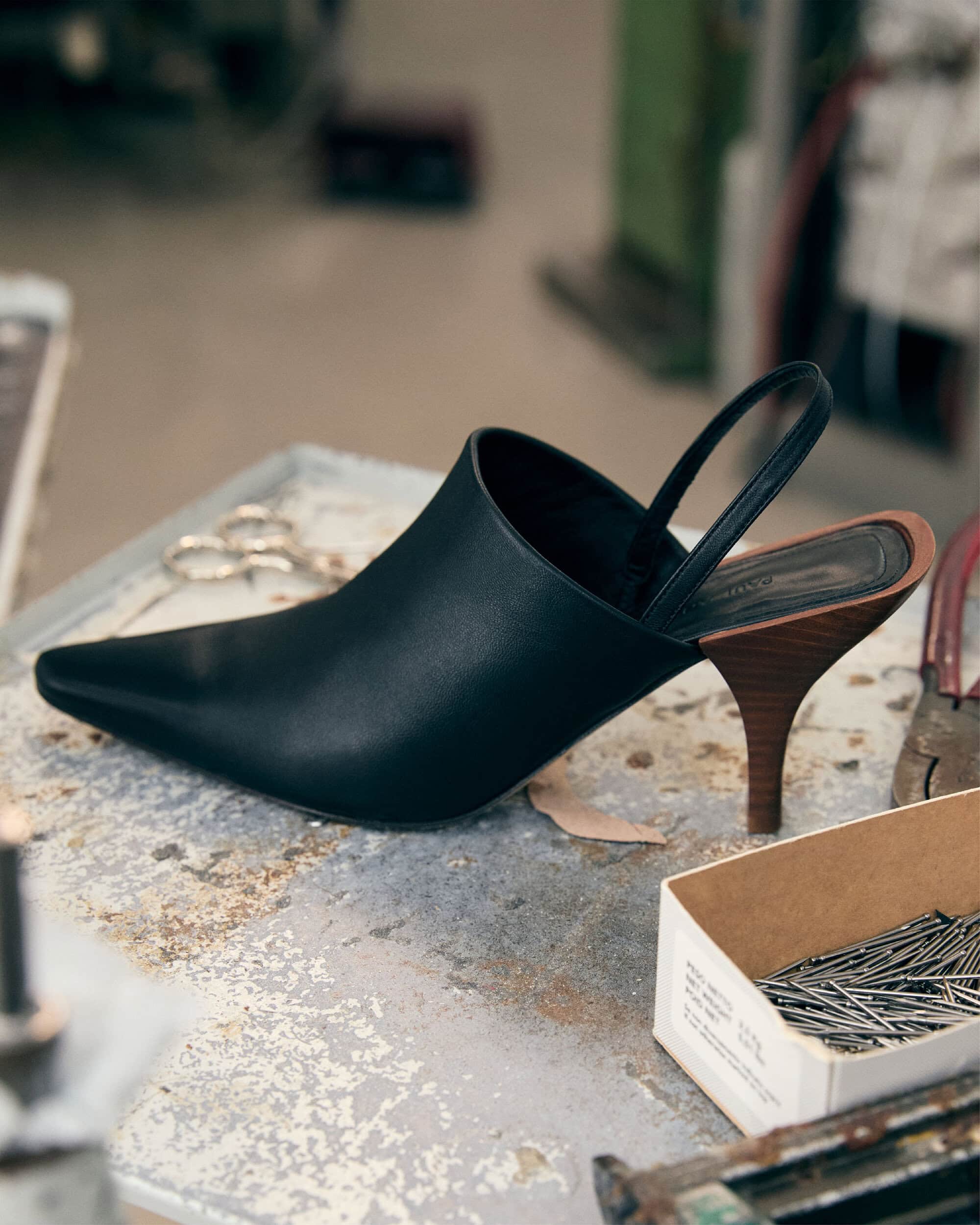 Black slingback pointed-toe heel with a wooden stiletto on a worn workbench
