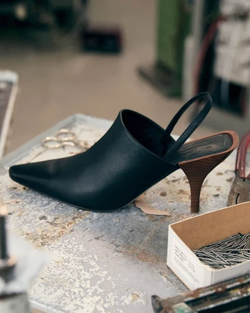 Black slingback pointed-toe heel with a wooden stiletto on a worn workbench