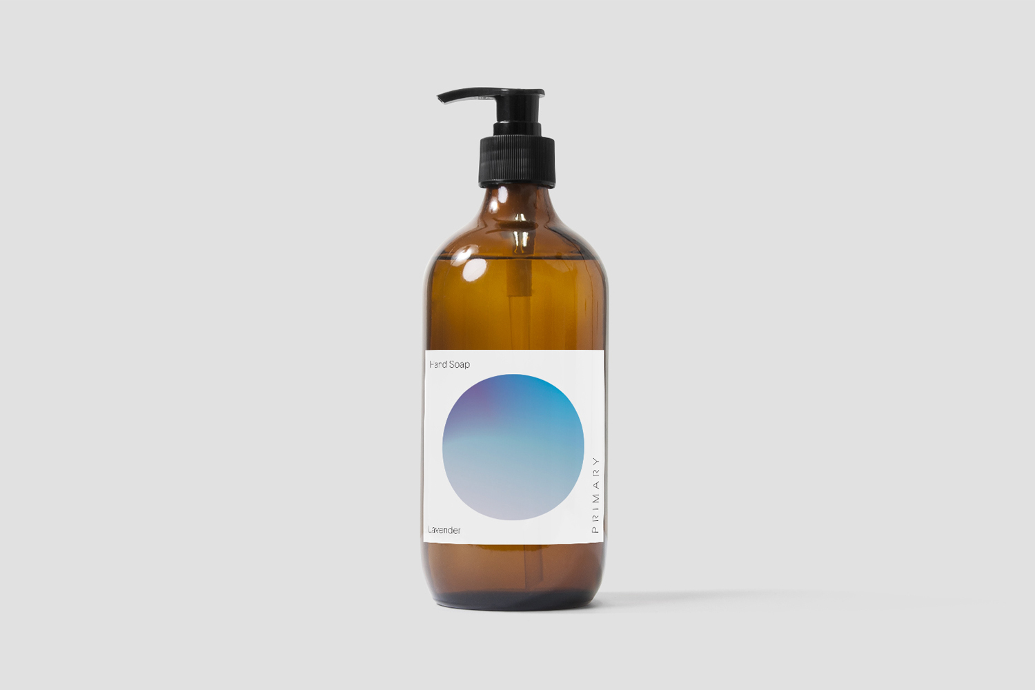 Amber glass pump bottle of hand soap with a white label featuring a blue and purple gradient circle on a plain light grey background.
