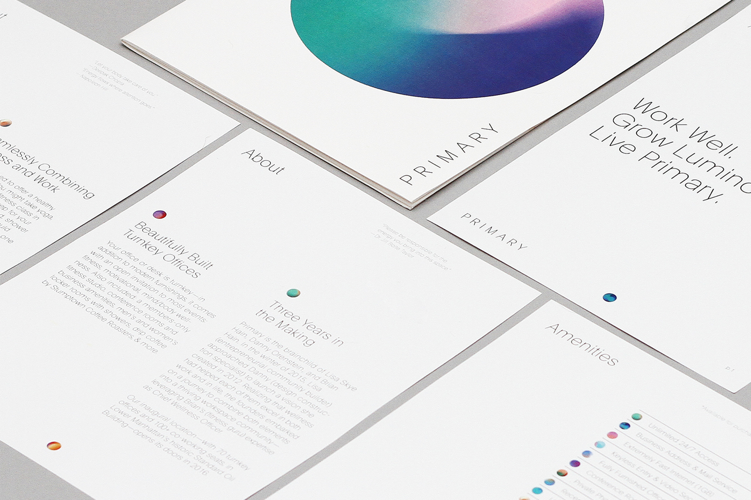 Close-up of printed brand identity collateral and brochures featuring minimalist typography and colourful gradient graphic elements on white paper.