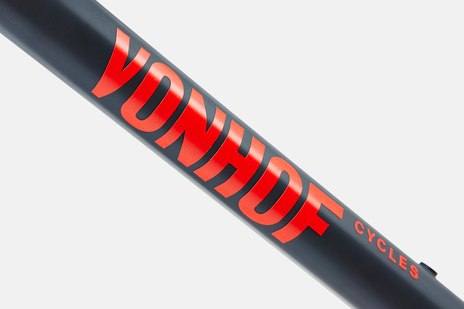 Close-up macro shot of red typography branding on a dark matte bicycle frame against a clean white background