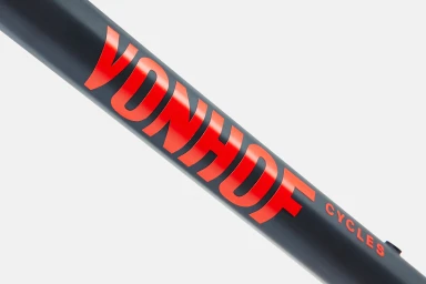 Close-up macro shot of red typography branding on a dark matte bicycle frame against a clean white background