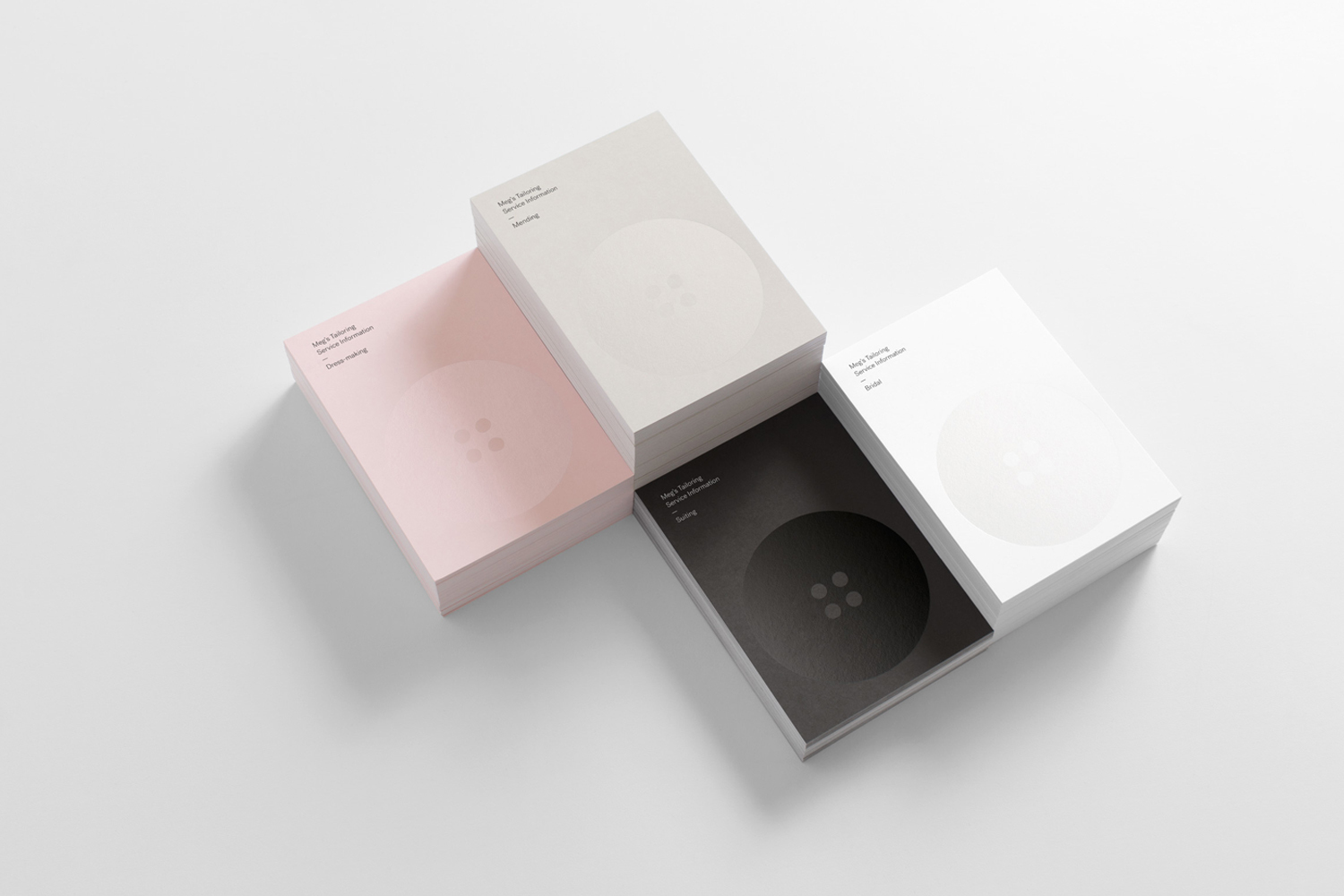 Four stacks of business cards in pink, beige, white, and black arranged on a white background