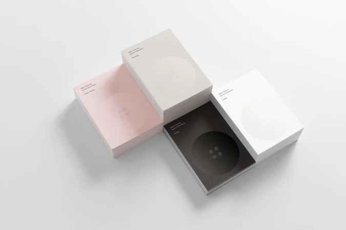 Four stacks of business cards in pink, beige, white, and black arranged on a white background
