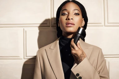 Willow Smith holding a Dior makeup stick wearing a camel blazer against a panelled wall