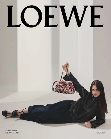 Model Raffey Cassidy in black leather holding a textured patterned handbag for Loewe Fall 2025 ad campaign.