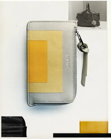 Loewe leather wallet with geometric yellow inlay and zipper pull against a white background