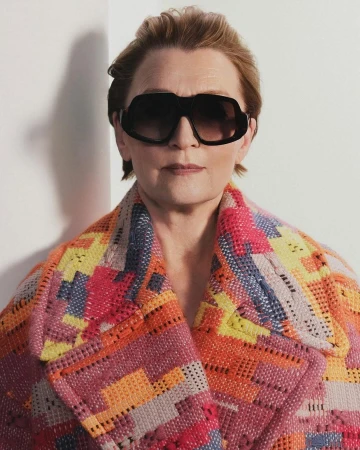 Lesley Manville wearing dark oversized sunglasses and a colourful knit coat against a white background for Loewe.