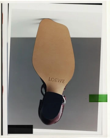 Close-up of a designer shoe sole featuring the Loewe brand name against a neutral studio background.
