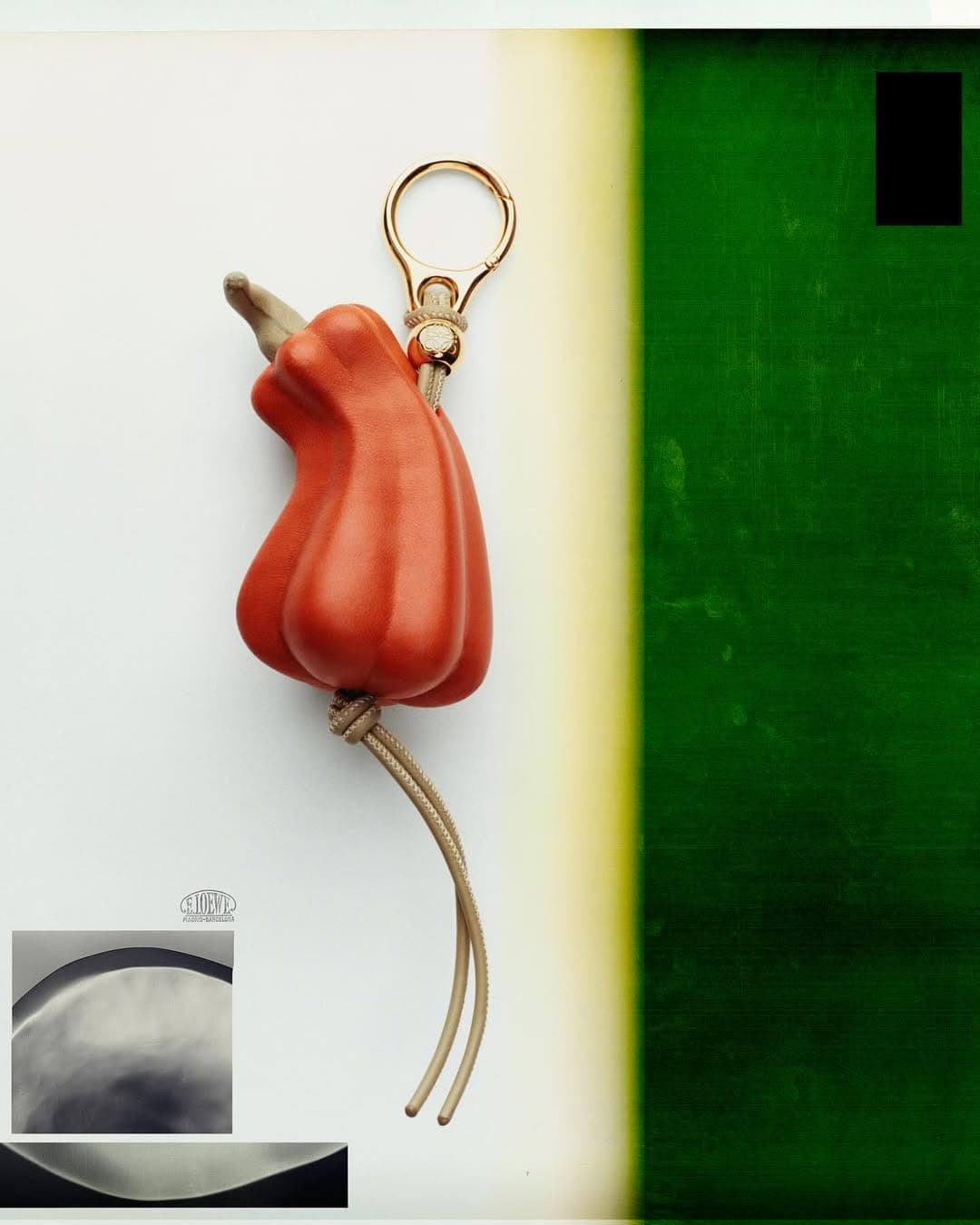Close-up of a sculpted orange leather chili pepper charm with gold hardware against a split white and green background.
