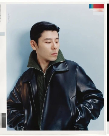 Man wearing a black leather jacket with a green ribbed collar against a pale blue background for the Loewe Fall 2025 ad campaign.