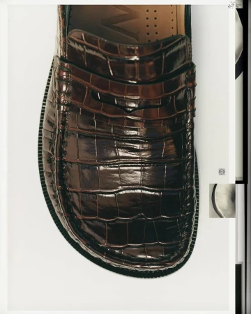 Close-up shot of a glossy brown embossed leather loafer on a clean white background for Loewe.