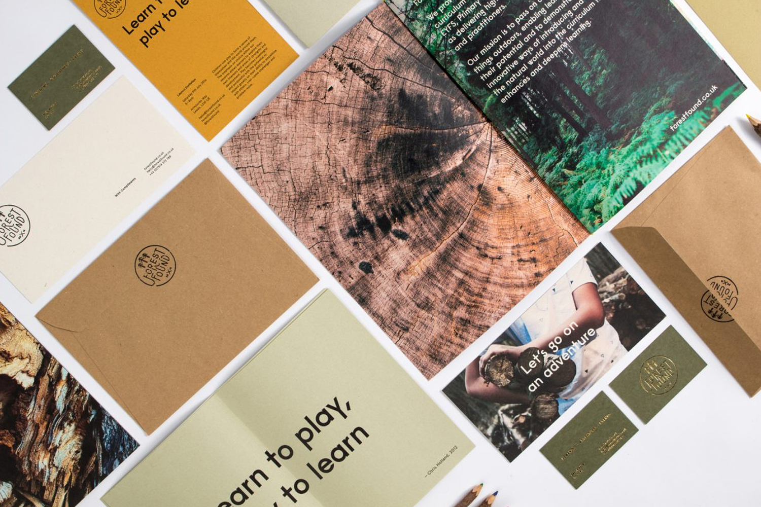 Flat lay of Forest Found brand identity stationery, kraft envelopes, and brochures on a white surface.