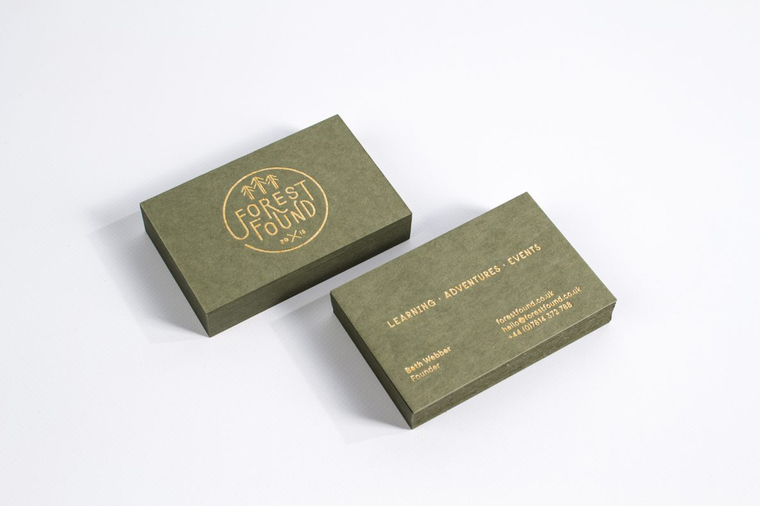 Two olive green business cards with gold foil stamping displayed on a clean white background.