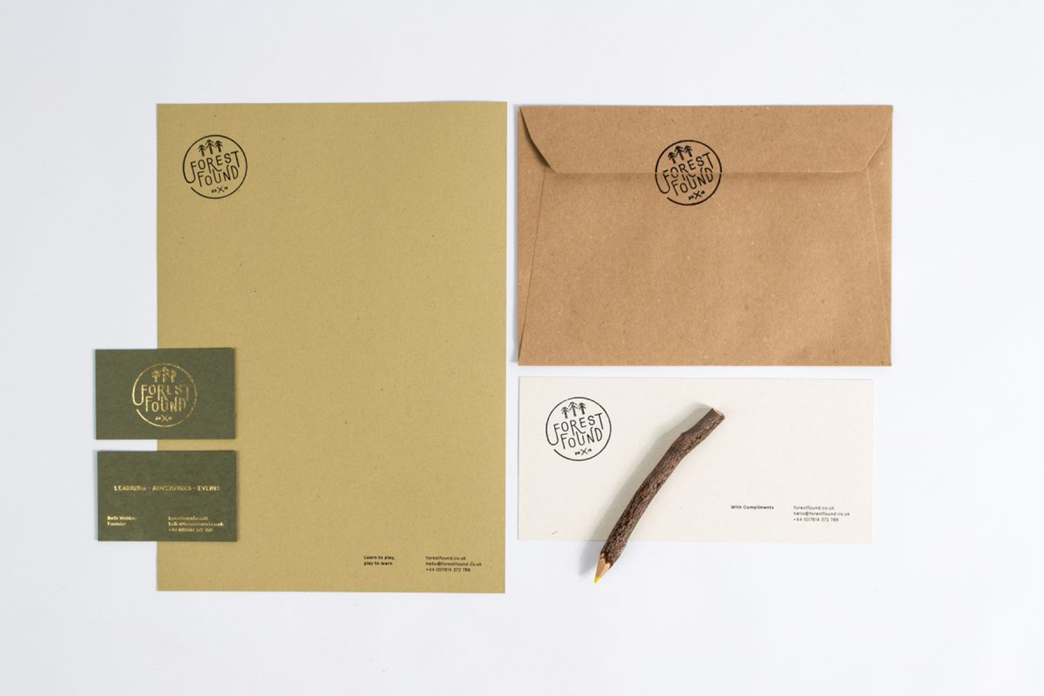 Branding stationery mockup featuring Forest Found logo on kraft paper letterhead, envelopes, business cards, and a twig pencil.