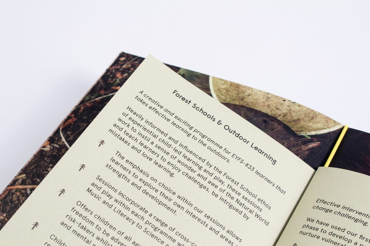 Close-up of an open printed booklet displaying typographic text on cream paper against a plain white background