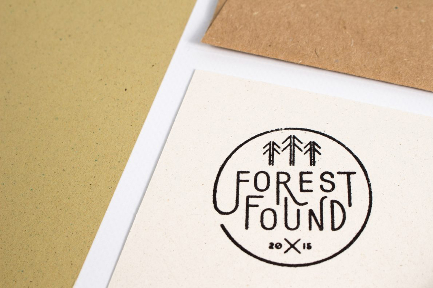 Close up overhead shot of Forest Found brand identity stationary with a stamped tree logo on textured white paper.