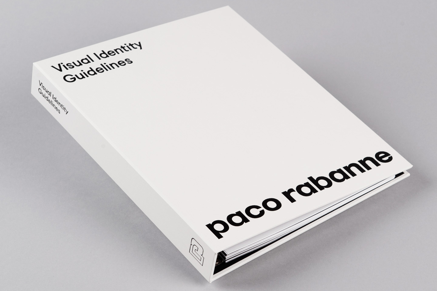 White ring binder featuring bold black paco rabanne typography on a neutral grey studio background