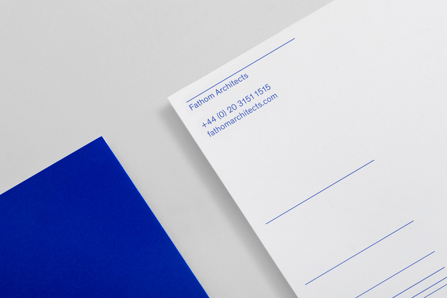 Fathom Architects brand identity stationery with blue typography on white paper alongside a vibrant blue shape.