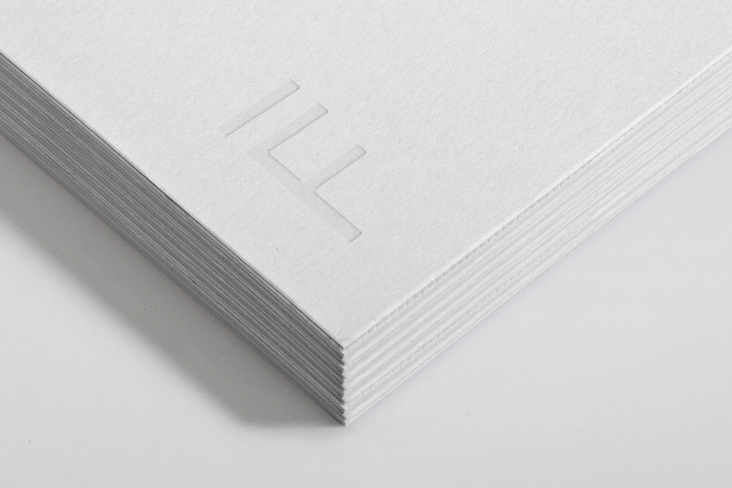 Close-up of a thick stack of white textured paper with an embossed architectural logo on top
