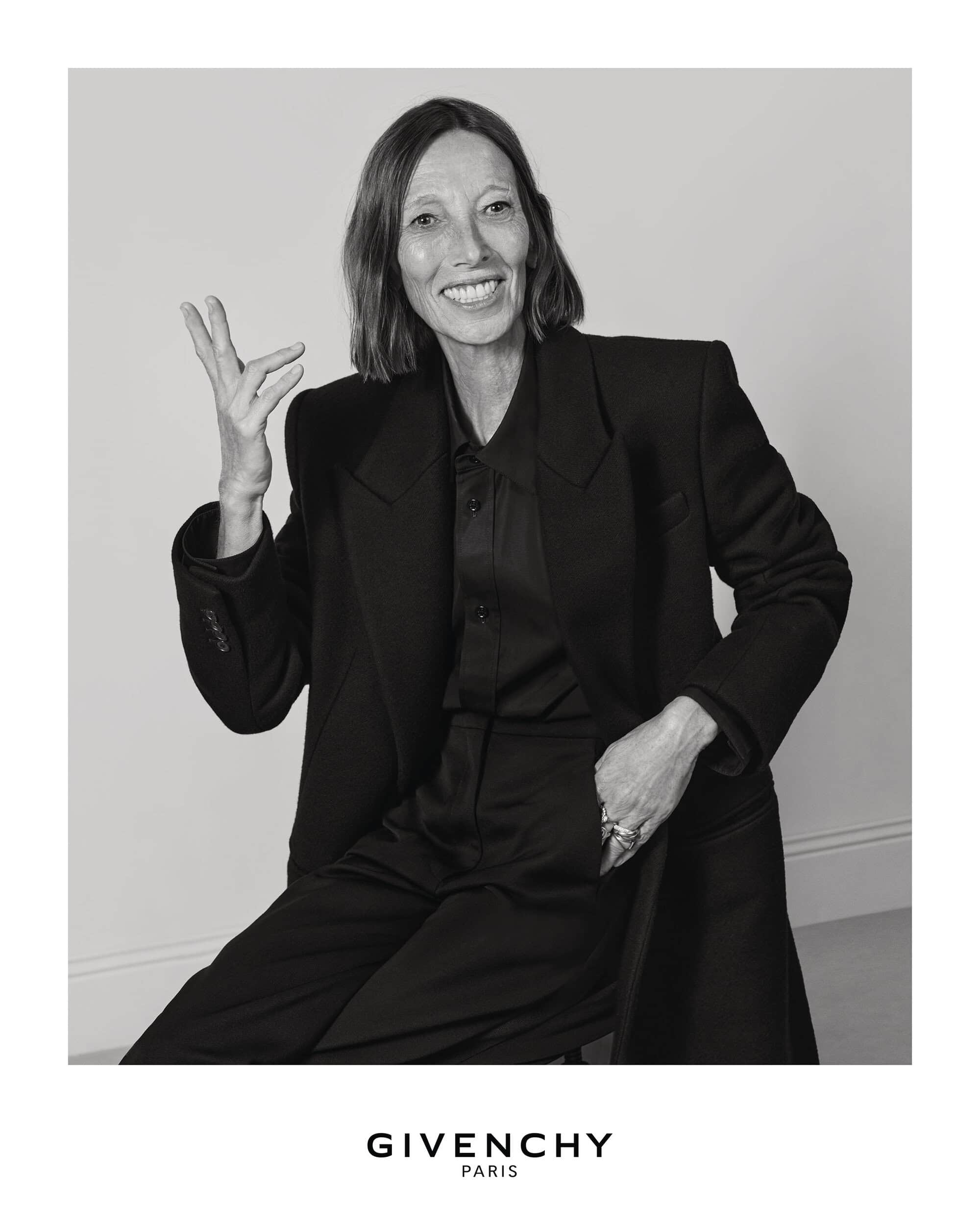 Portrait of a smiling woman wearing a dark blazer and shirt against a plain background for the Givenchy Fall 2025 campaign.