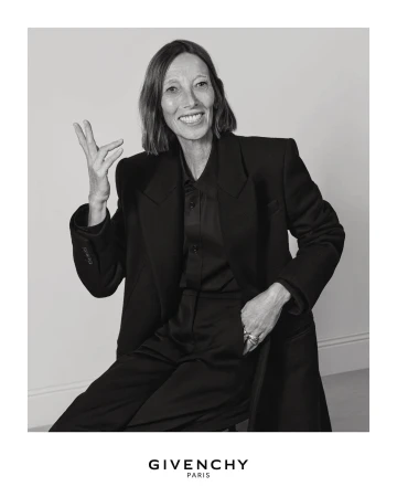 Portrait of a smiling woman wearing a dark blazer and shirt against a plain background for the Givenchy Fall 2025 campaign.