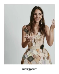 Model wearing a structured dress adorned with cosmetic compacts and mirrors against a light grey seamless background