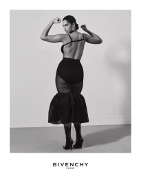 Model in black dress flexing biceps in Givenchy Fall 2025 campaign shot by Collier Schorr against a plain grey studio backdrop