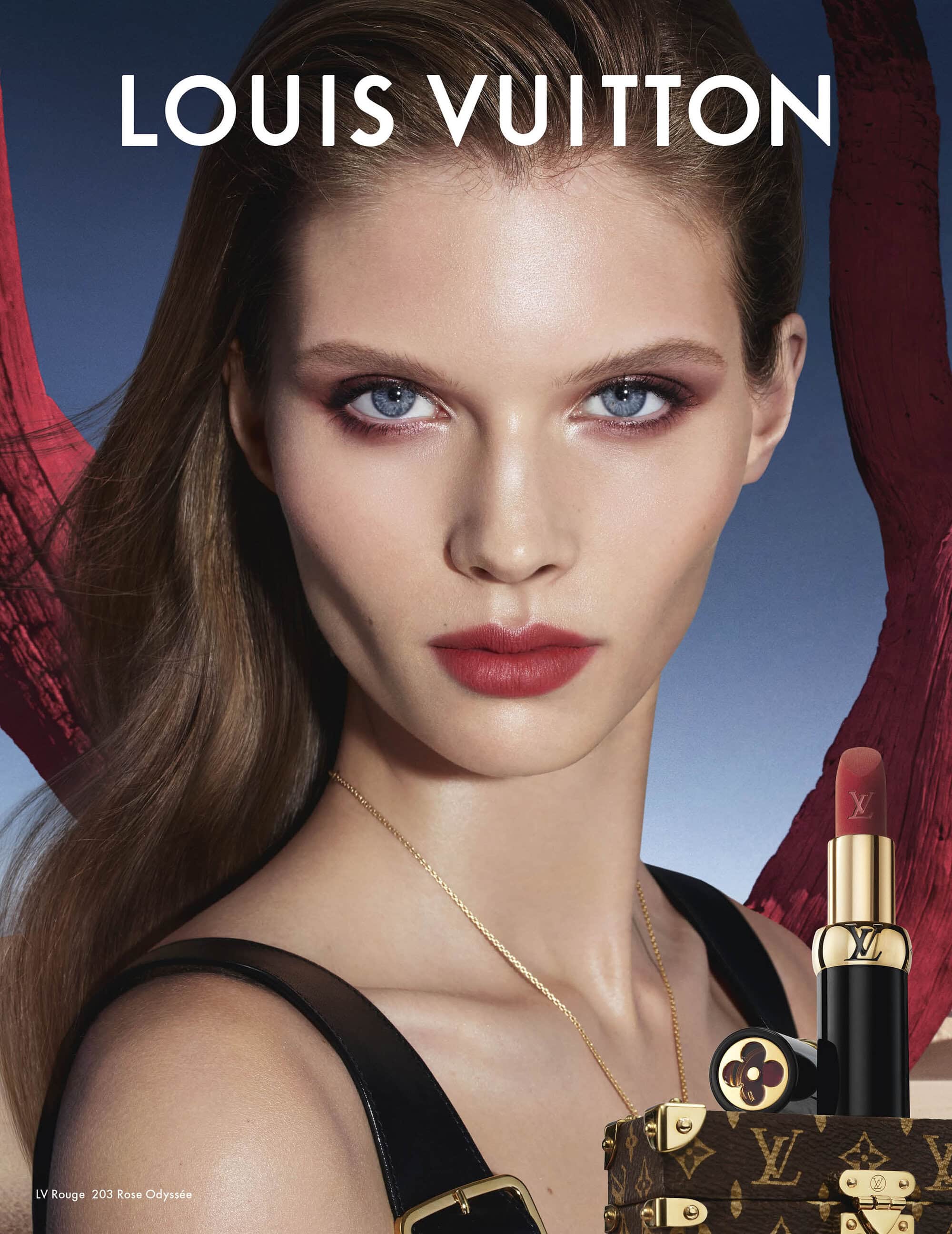 Close-up beauty portrait of a model with blue eyes wearing dark lipstick and a gold necklace for a Louis Vuitton ad campaign
