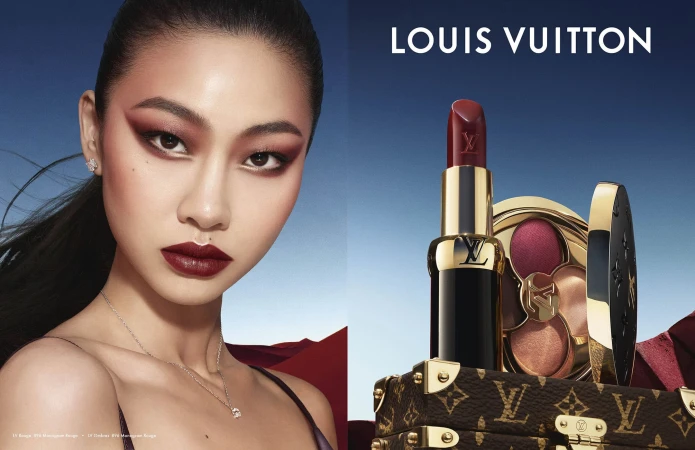 Close-up portrait of an East Asian model alongside Louis Vuitton lipstick and compact against a gradient sky background.